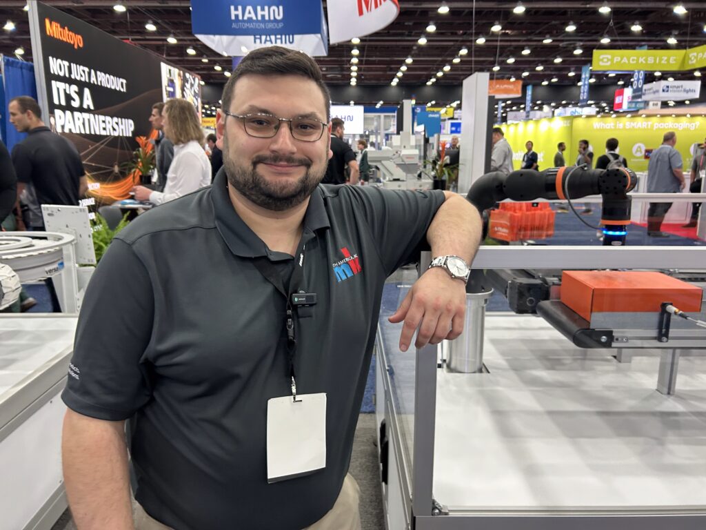 Scott Blais Jr., sales and development manager at mk North America, poses with the company’s shuttle system, an energy-efficient machine that reduces usage.