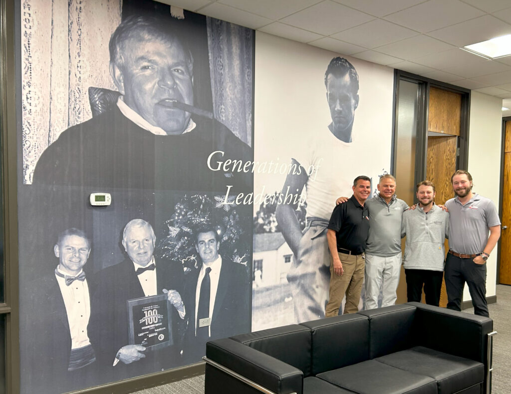 Fourth-generation family leadership at Conveyer & Caster: Trevor, Jeff, Travis, and Tyler Stohr stand in front of the “Generations of Leadership” mural honoring Albert Stohr Sr. and Albert Stohr Jr.’s family legacy.