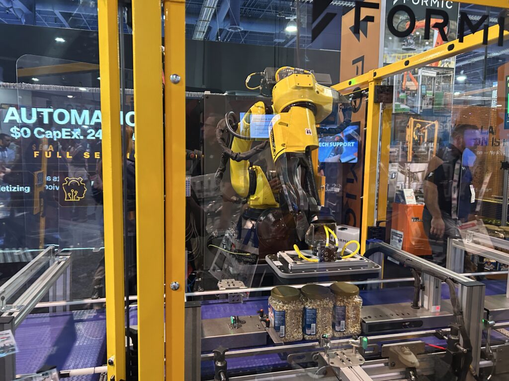 Formic demonstrated a new case packing solution moving food containers at Pack Expo at the Las Vegas Convention Center. The system integrates robotics and automation technology to streamline packaging operations.