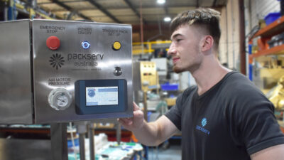 Operator using Packserv’s Industry 4.0-enabled PLC capping machine touchscreen HMI to manage production, reduce downtime, and simplify setup.