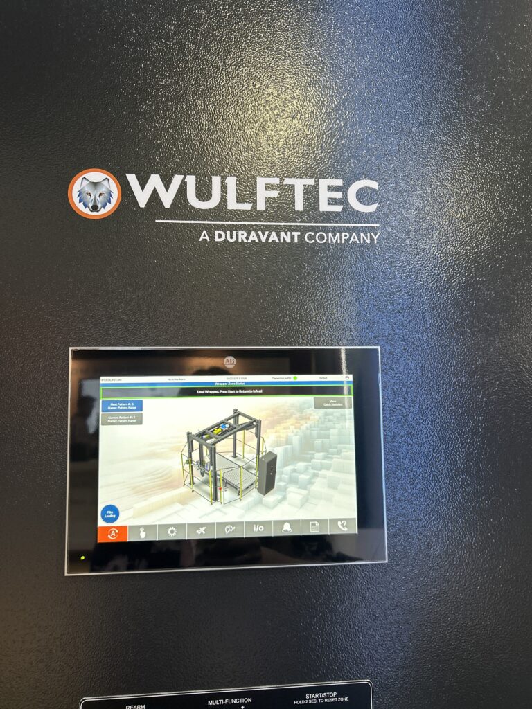 The Wulftec SMART series stretch wrapper HMI display at Modex 2026 in Atlanta, Georgia, showing system status messaging for end-of-line packaging operations, including load wrap and infeed cycle controls.