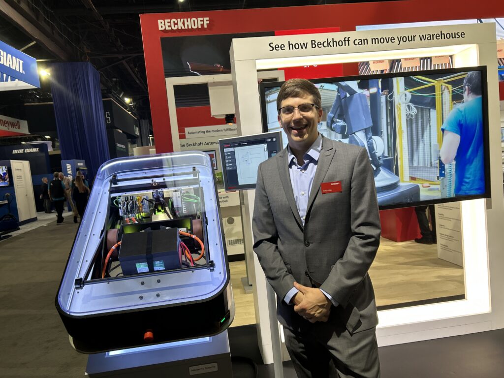 Nathan Hibbs, Material Handling & Intralogistics US Industry Manager at Beckhoff Automation USA, at the Beckhoff Automation booth during Modex 2026 in Atlanta, Georgia. He is standing next to a demo showing how Beckhoff technology can be used for autonomous mobile robots.
