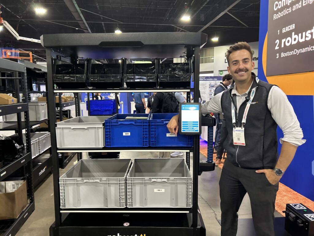 Will McInnis at Robust.AI standing next to Carter at Modex 2026 in Atlanta, Georgia, showcasing the robot’s AI-enabled navigation and safety capabilities.