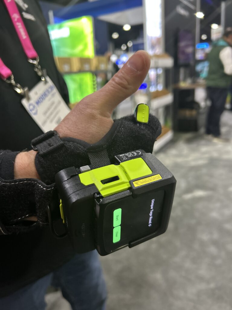 Dan Baldwin, global product manager at Zebra Technologies, demonstrating Zebra’s WS501-R RFID wearable computer at Modex 2026 in Atlanta, Georgia, showing the device’s handheld form factor and built-in RFID and barcode scanning capabilities.