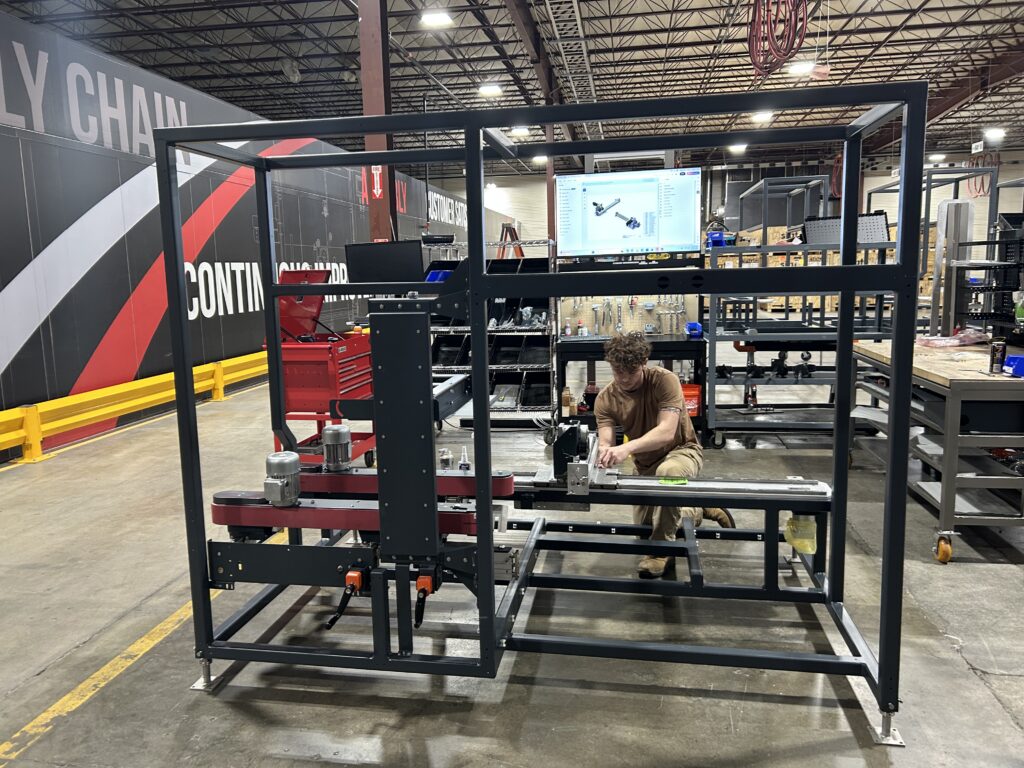 Ethan Foss, assembly, working on end-of-line equipment on the shop floor at Combi Packaging Systems in Canton, Ohio as part of custom machine builds across the production bays.