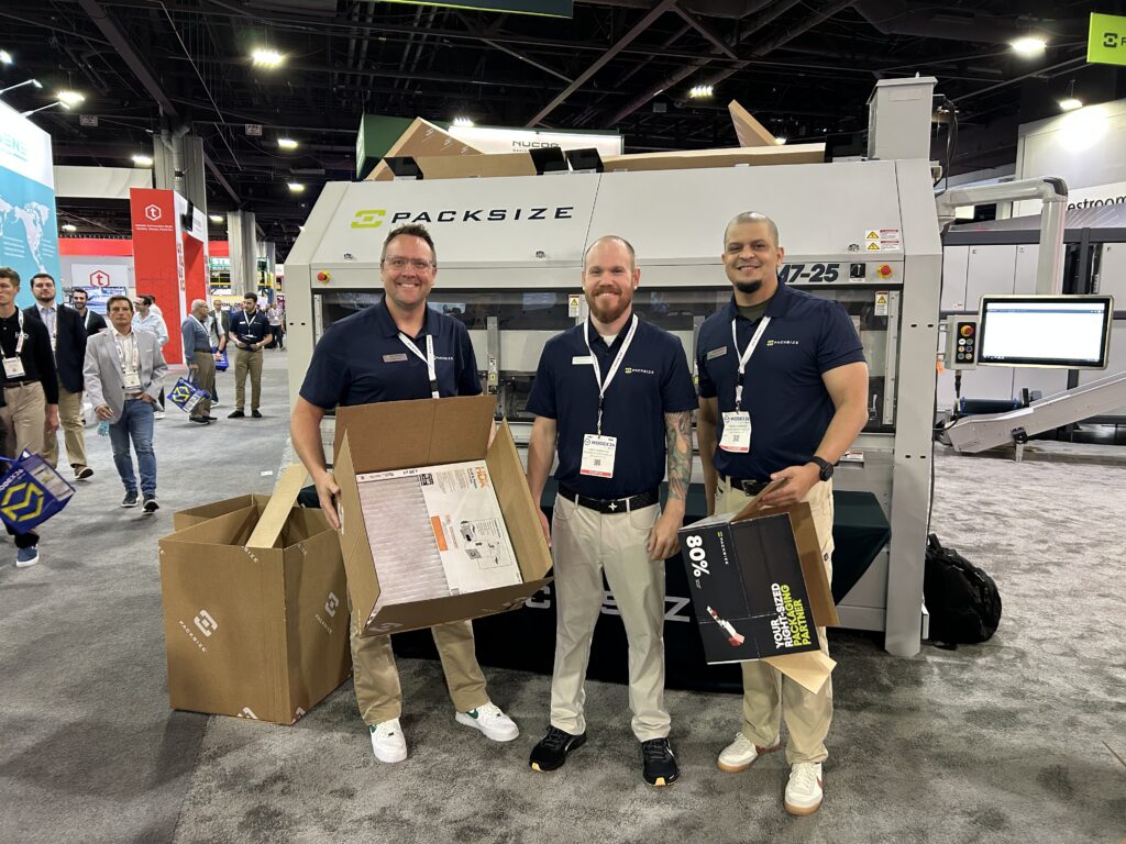 Adam Fray, vice president of global marketing at Packsize, and team members at Modex 2026 in Atlanta, Georgia, in front of the EM7 On Demand Packaging system, designed to support supply chain efficiency, warehouse space optimization, and reduced product damage and void fill.