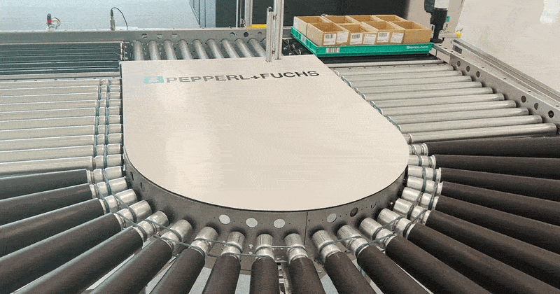 Pepperl+Fuchs industrial sensor lab demonstration shows photoelectric sensors and roller conveyors working together for zone-based conveyor control and real-time package movement detection.