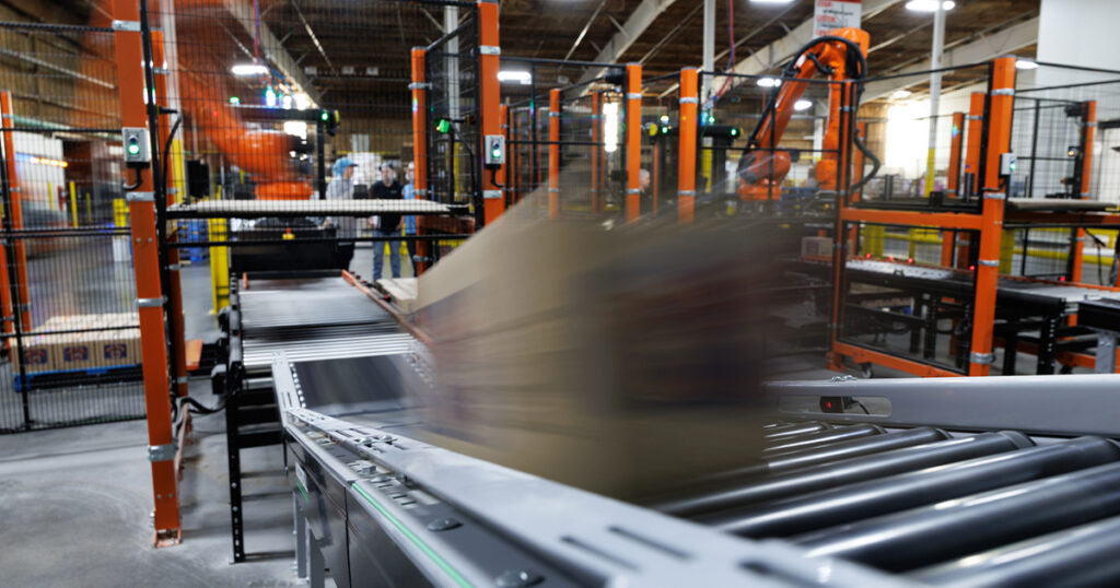 A filled box travels in motion down a conveyor ramp toward robotic palletizing at Wyandot Snacks in Marion, Ohio, illustrating end-of-line automation within a legacy manufacturing facility.