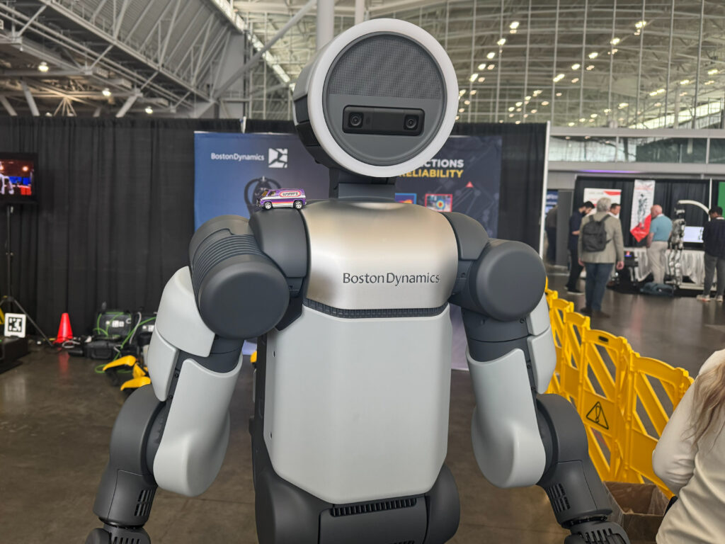 A Hot Wheels van sits atop Boston Dynamics’ Atlas humanoid robot on the show floor at the 2026 Robotics Summit & Expo in Boston.