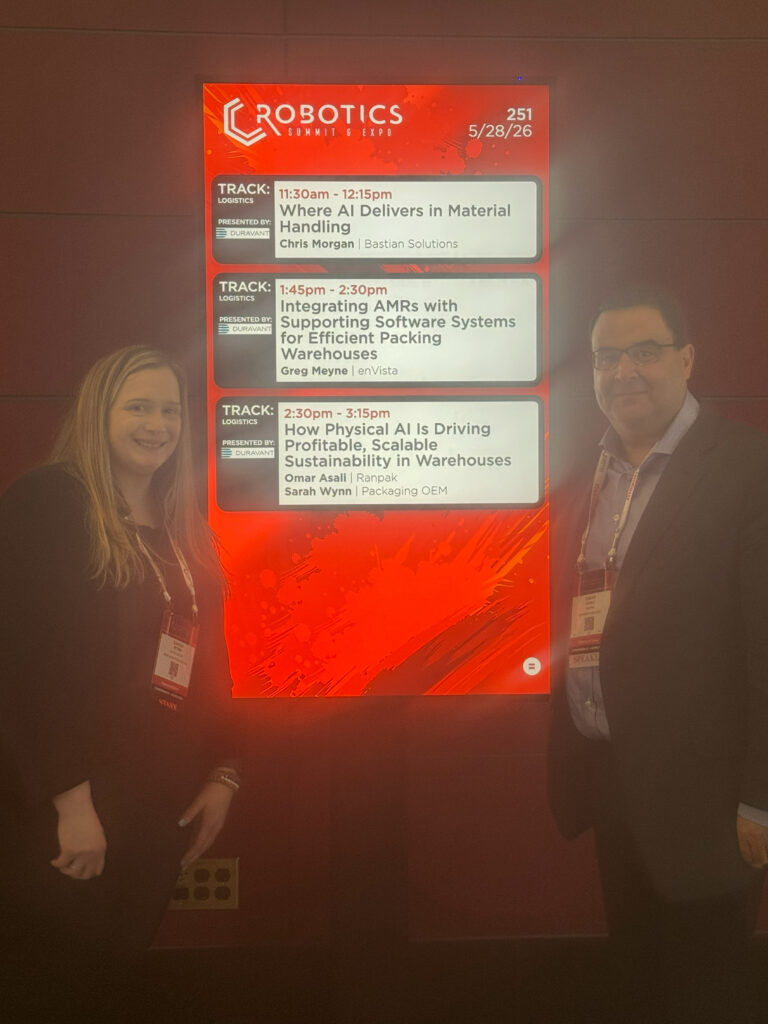 Ranpak CEO and chairman Omar Asali (right side of image) and Sarah Wynn, senior editor at Packaging OEM (left side of image), pose in front of signage for their session on how physical AI is driving profitable sustainability in the warehouse at the 2026 Robotics Summit & Expo in Boston.