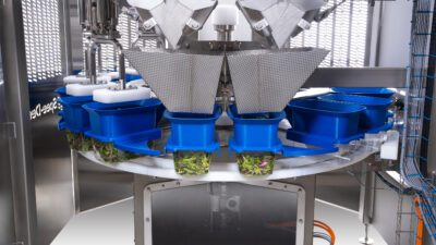 Spee-Dee Packaging Machinery’s rotary tray filler for high-speed filling of leafy greens and loose-fill products.