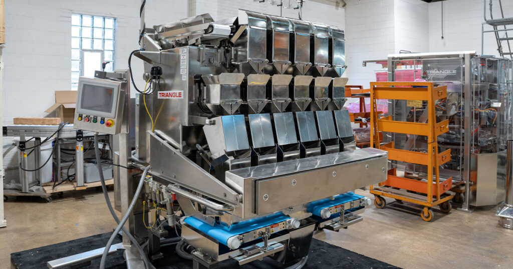 A multihead weigher manufactured by Triangle Package Machinery for weighing and portioning products in packaging applications.